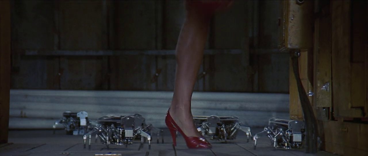 One leg in high heels surrounded by spider-robots. Still from movie Runaway (1984)